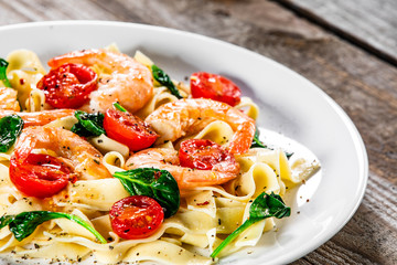 Shrimps with pasta tagliatelle with spinach and tomatoes