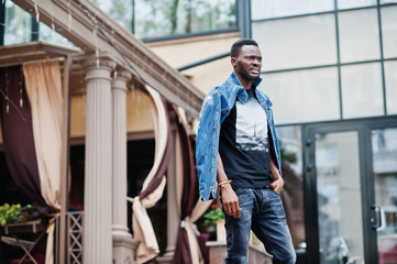 Young attractive serious african american man model. Modern handsome guy in jeans jacket standing on urban city street.