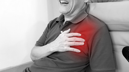 Elderly man suffering from chest pain with painful facial expression. Chest pain symptom may be...