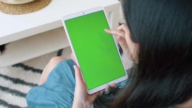 Woman uses tablet with green screen for watching video, shopping online and texting in social networks. 4k slow motion footage.