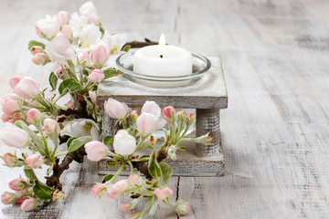 White candle and apple tree twig on rustic wooden table.