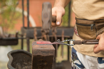Blacksmith working on metal on an anvil in the forge