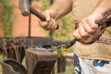 Blacksmith working on metal on an anvil in the forge