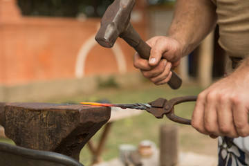 Blacksmith working on metal on an anvil in the forge