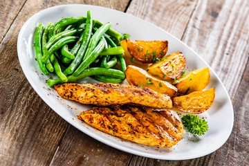 Grilled chicken fillets, baked potatoes and green beans
