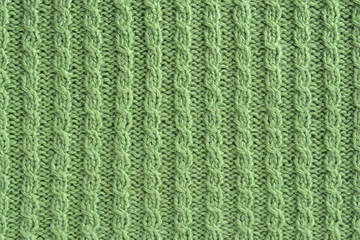 Light green knitted texture, background. Hand knitted cable pattern.