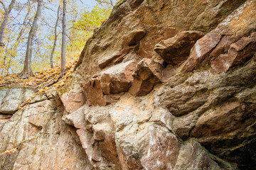 Stone mountain in the autumn forest with fallen leaves