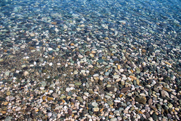 Sea stones in sea water. Pebbles under water. The view from the top. Nautical background. Clean sea water. Transparent sea.
