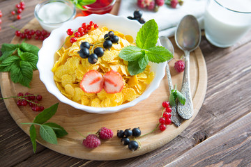 Fresh corn flakes with strawberries and milk close up Healthy tasty breakfast cornflakes with strawberries, raspberries, black currants and red currants.