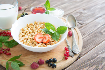 Breakfast cereal on a rustic wood background, overhead view Healthy tasty breakfast of muesli with strawberries, raspberries, black currants and red currants.