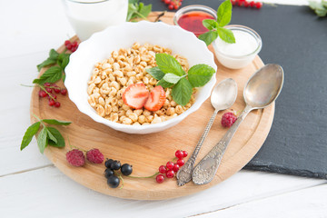 Healthy breakfast. Oatmeal with berries and honey. Healthy tasty breakfast of muesli with strawberries, raspberries, black currants and red currants.