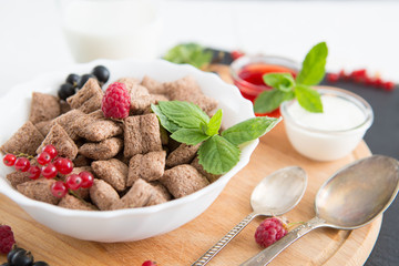 chocolate cereal pads with berries in bowl Healthy tasty breakfast chocolate square pads with strawberries, raspberries, black currants and red currants.