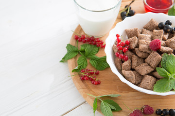 chocolate cereal pads with berries in bowl Healthy tasty breakfast chocolate square pads with strawberries, raspberries, black currants and red currants.