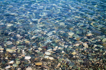 Sea stones in sea water. Pebbles under water. The view from the top. Nautical background. Clean sea water. Transparent sea.