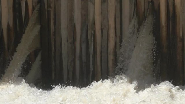 The old wooden causeway (gauging station) is leaking and water gushes through the logs, dam without overflow, failure of dam. Super slow motion 1000 fps