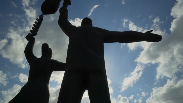 Close-up: Male and female stone statues in city against bright sky - Novosibirsk, Russia
