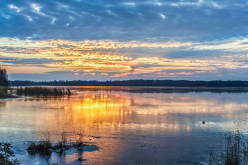 Colorful sunset on the lake covered with the first ice