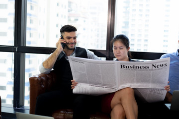 young business woman reading newspaper to update her team before meeting