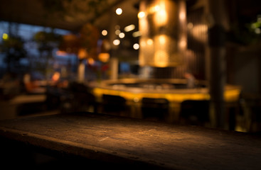 Obraz na płótnie Canvas Empty wood table top on blur light gold bokeh of cafe restaurant in dark background