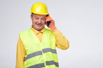 Repairman in protective helmet talking on his phone with client