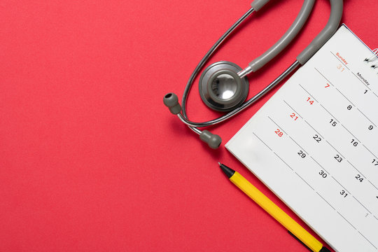 Top view of stethoscope and calendar on the red background, schedule to check up healthy concept