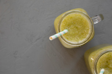 Homemade green cucumber apple smoothie in glass jars on a gray background, top view. Flat lay, overhead, from above. Copy space.