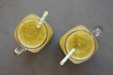Homemade green cucumber apple smoothie in a glass jar on a concrete background, top view. Flat lay, overhead, from above.