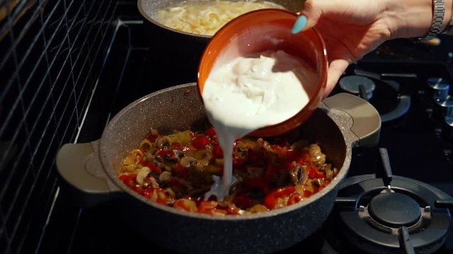 the woman adding the cream in to the pan