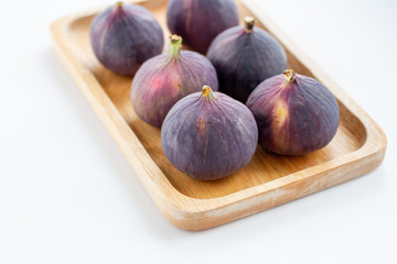 fresh figs in a wooden plate on white background