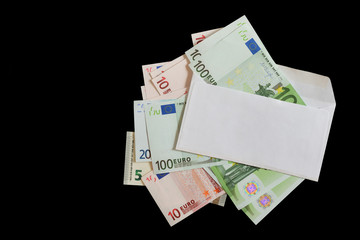 White envelope on a pile of different Euro banknotes isolated on a black background. Top view. Copy space