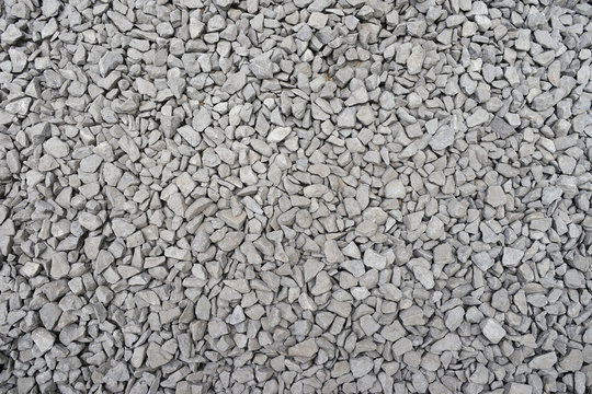 Dirty gravel ballast background. Small gray dusty broken stones texture. Top view