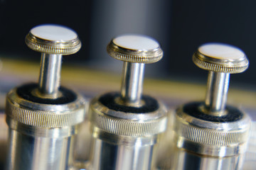 The silver trumpet pipe valves on the defocused background. Musical instrument photography.