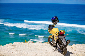 Obraz premium Custom made motorcycle parked on the odge of a cliff near the ocean.