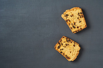 Two scattered pieces of tasty sweet homemade bread with raisin lies on dark concrete table on kitchen. Space for text. Flat lay