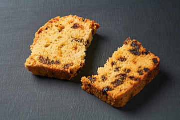 Two broken pieces of tasty sweet homemade bread with raisin lies on dark concrete table in kitchen. Close-up