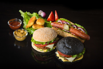 Delicious fast food. Two hamburgers with beef burger cutlet, fried onion, spinach, ketchup sauce and blue cheese in traditional buns, served on wood chopping board over dark wooden background.