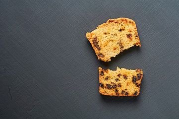 Broken pieces of tasty sweet homemade bread with raisin lies on dark concrete table in kitchen. Space for text. Flat lay