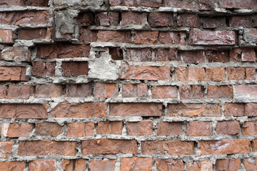 Old weathered red brick wall. Wall with fallen off plaster and crumbling bricks 
