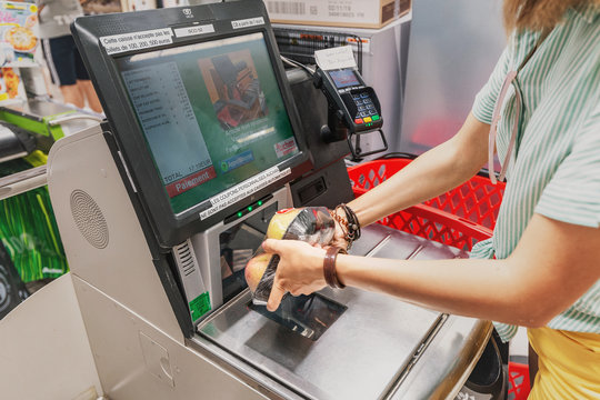 23 July 2019, Auchan supermarket, Lyon, France: Girl customer scans products at the self-service checkout in the grocery shop