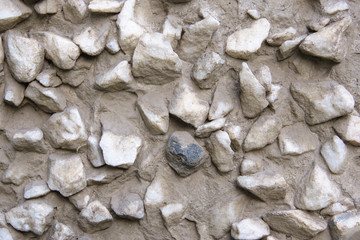 Stones in concrete for background. Black in the center, bright around the edges. Texture.