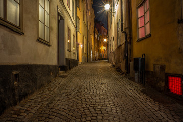 Fototapeta na wymiar Old cobbled colorful narrow street in Stockholm at night - 5