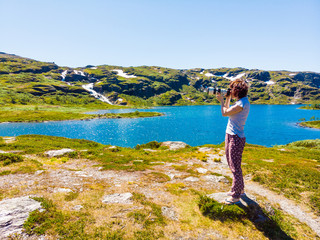 Naklejka na ściany i meble Tourist taking photo in norwegian nature