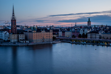Fototapeta premium A colorful sunrise over Stockholm with the lights reflecting on the calm water of the sea - 6