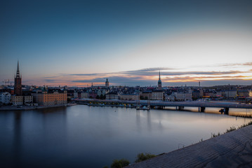 Fototapeta na wymiar A colorful sunrise over Stockholm with the lights reflecting on the calm water of the sea - 7