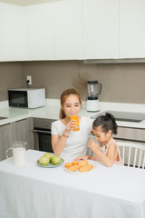 Obraz na płótnie Canvas Asian children and her mom drink orange juice in the morning