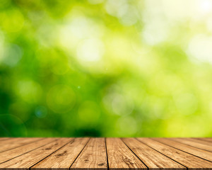 Brown wood surface on a green background. Green leaf background, blurred sun, abstract bokeh can be used for displaying or editing your product.