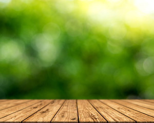 Brown wood surface on a green background. Green leaf background, blurred sun, abstract bokeh can be used for displaying or editing your product.