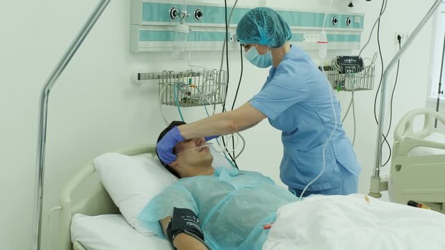 nurses wear an oxygen mask to a patient in intensive care