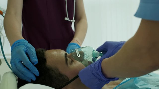 nurses wear an oxygen mask to a patient in intensive care
