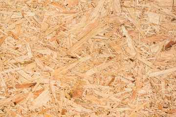 OSB boards are made of brown wood chips sanded into a wooden background. Top view of OSB wood veneer background, tight, seamless surfaces.